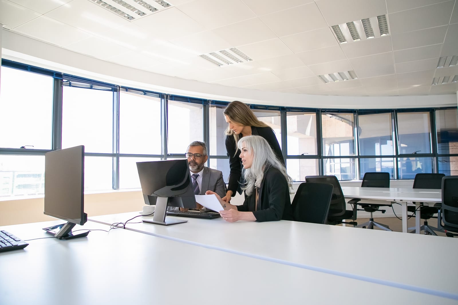 Gruppo al tavolo che segue una presentazione su monitor durante una riunione